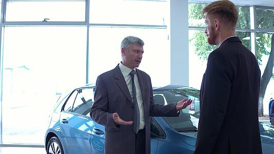 汽车展厅的帅哥和汽车经销商谈话视频的预览图