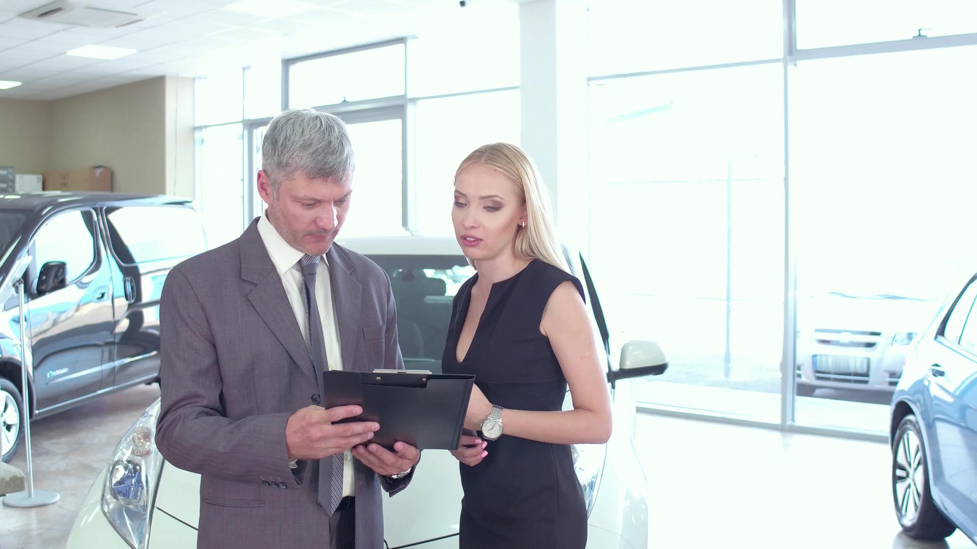在汽车展厅与汽车经销商交谈的年轻女子视频的预览图