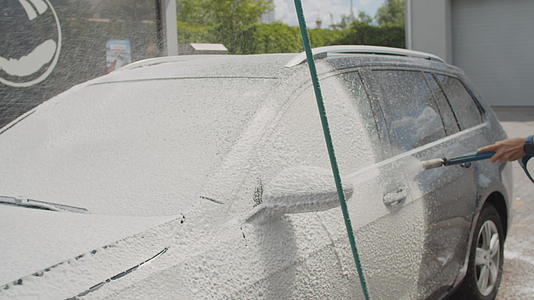 30岁的年轻女性在自助洗车时清洗家用汽车外面洗车视频的预览图
