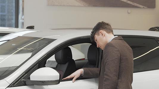 一个成熟的男人看着经销商卖的新车里的一辆新车视频的预览图