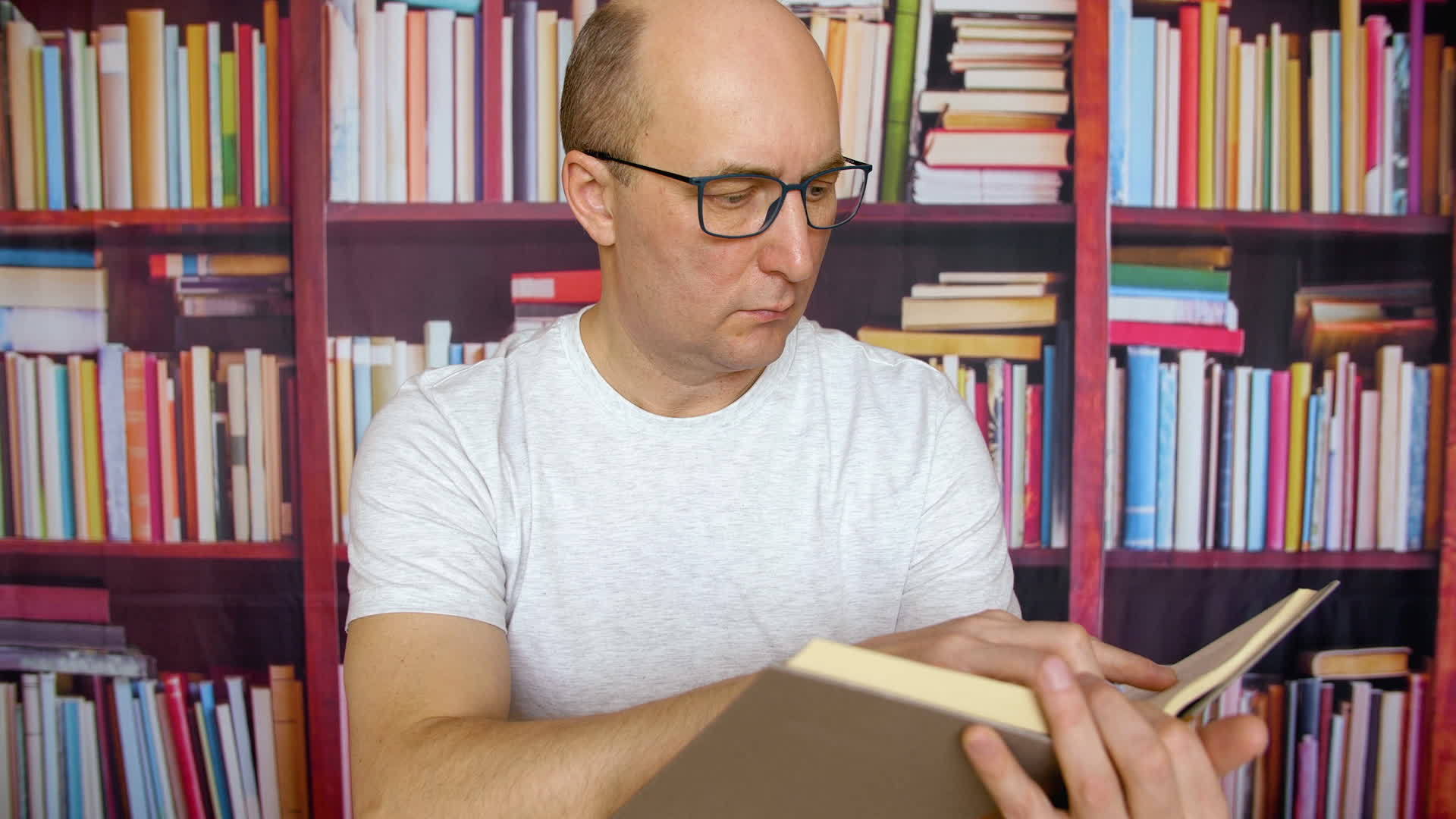 体贴的白人在图书馆的书架背景上戴着眼镜和白色视频的预览图