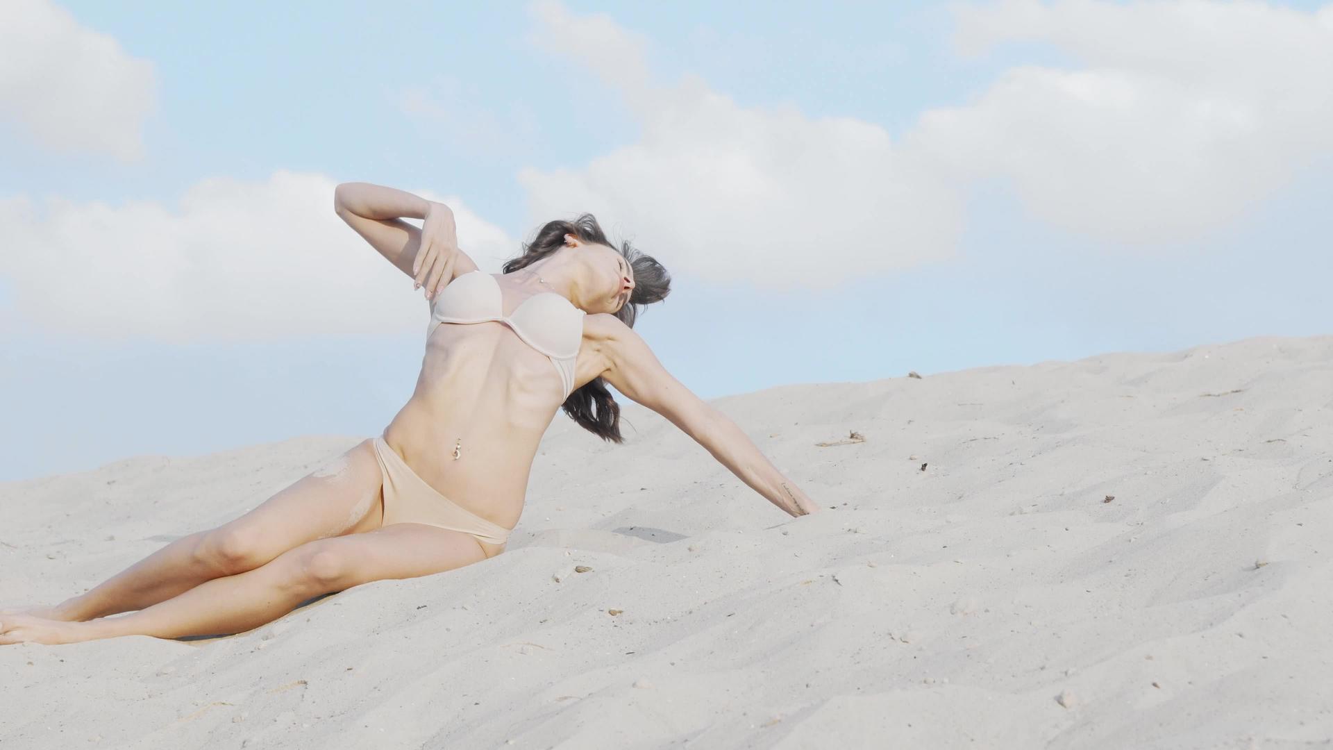 穿着米色比基尼的漂亮女人在沙漠海滩上打扮视频的预览图
