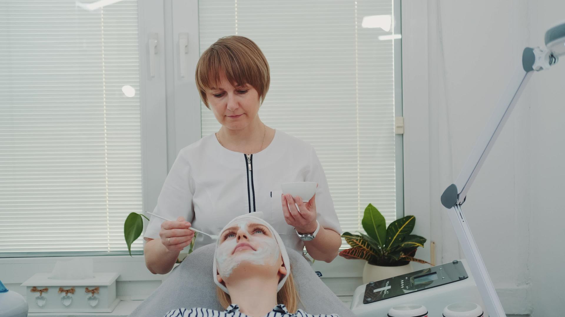 美容师在美容院给女人脸上涂上奶油面罩视频的预览图