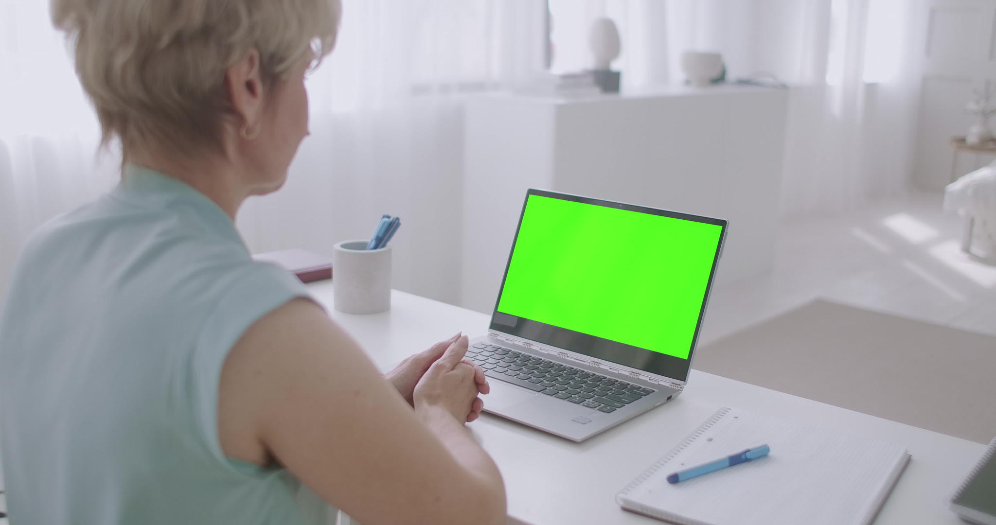 金发金发女性通过视频电话在线查看笔记本电脑的绿色视频的预览图