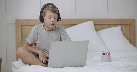 男孩通过笔记本电脑在家与同学或家长聊天视频的预览图