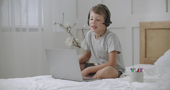快乐的男孩正在用笔记本电脑通过视频电话与某人交流视频的预览图