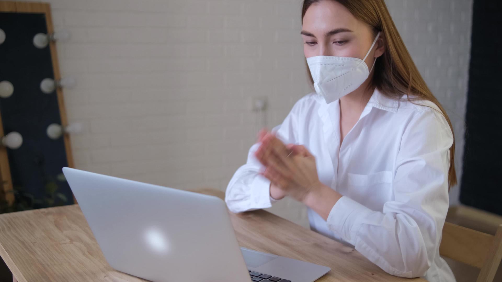 一名戴着医用口罩的远程员工使用从家庭办公室开始的应用程序视频的预览图