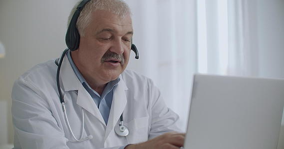 治疗师正在使用带有互联网和耳机的笔记本电脑视频的预览图