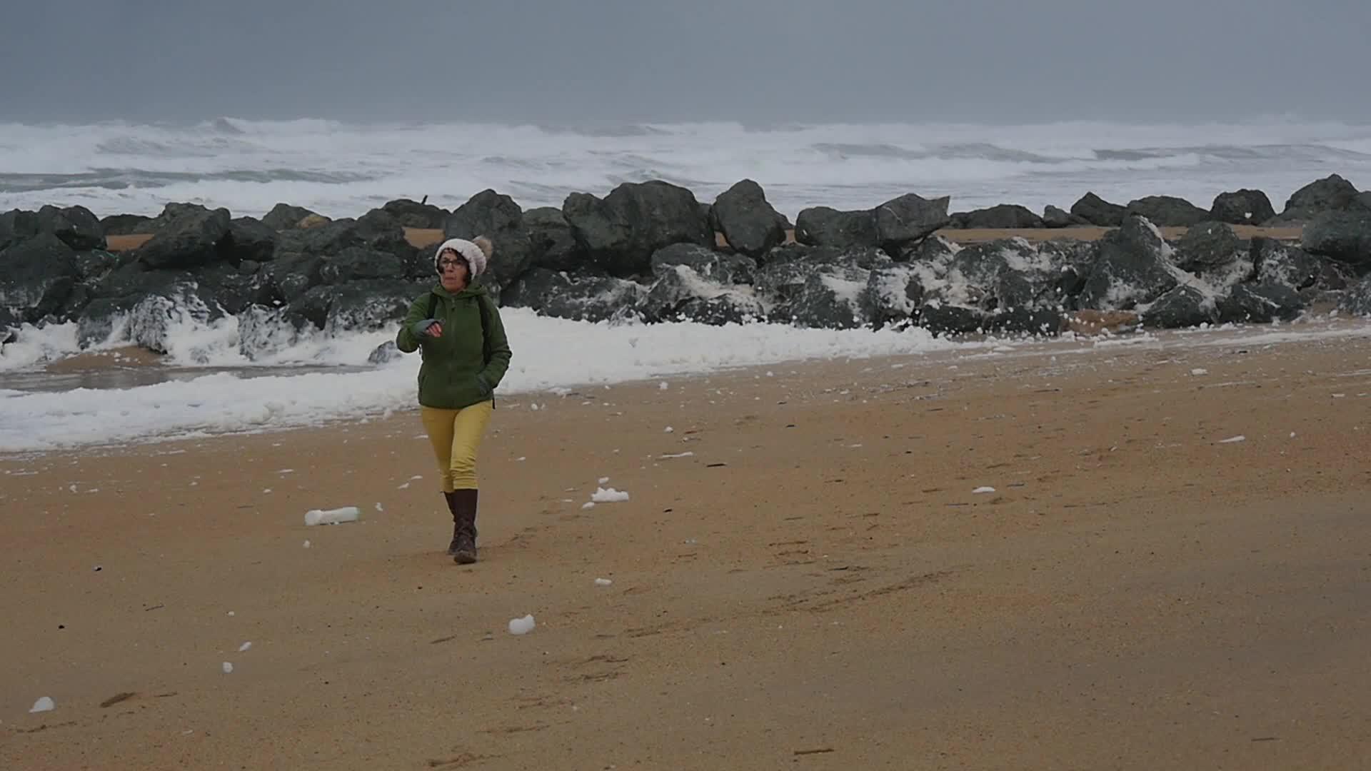 女人在海滩上行走暴风雨中视频的预览图