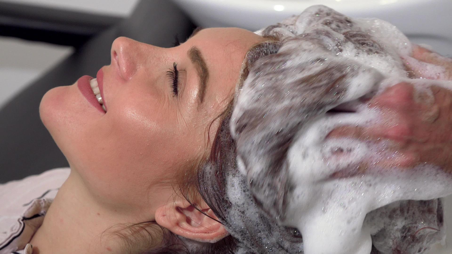 女性享受头部按摩理发师洗头视频的预览图