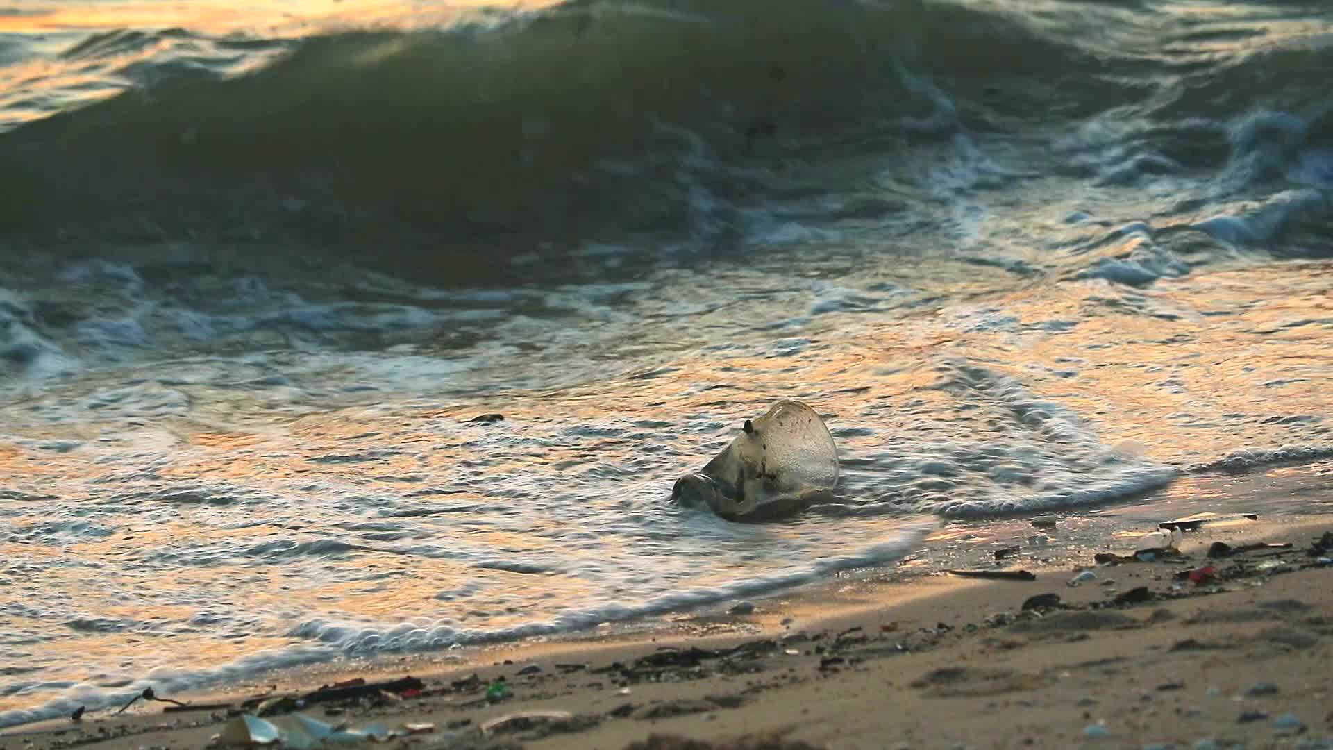 塑料玻璃和废物海浪留在海上把它们吹进海里视频的预览图