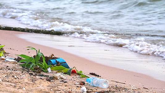 海边日落的海滩上有塑料和底部的废物 海浪把它们吹进海里视频的预览图