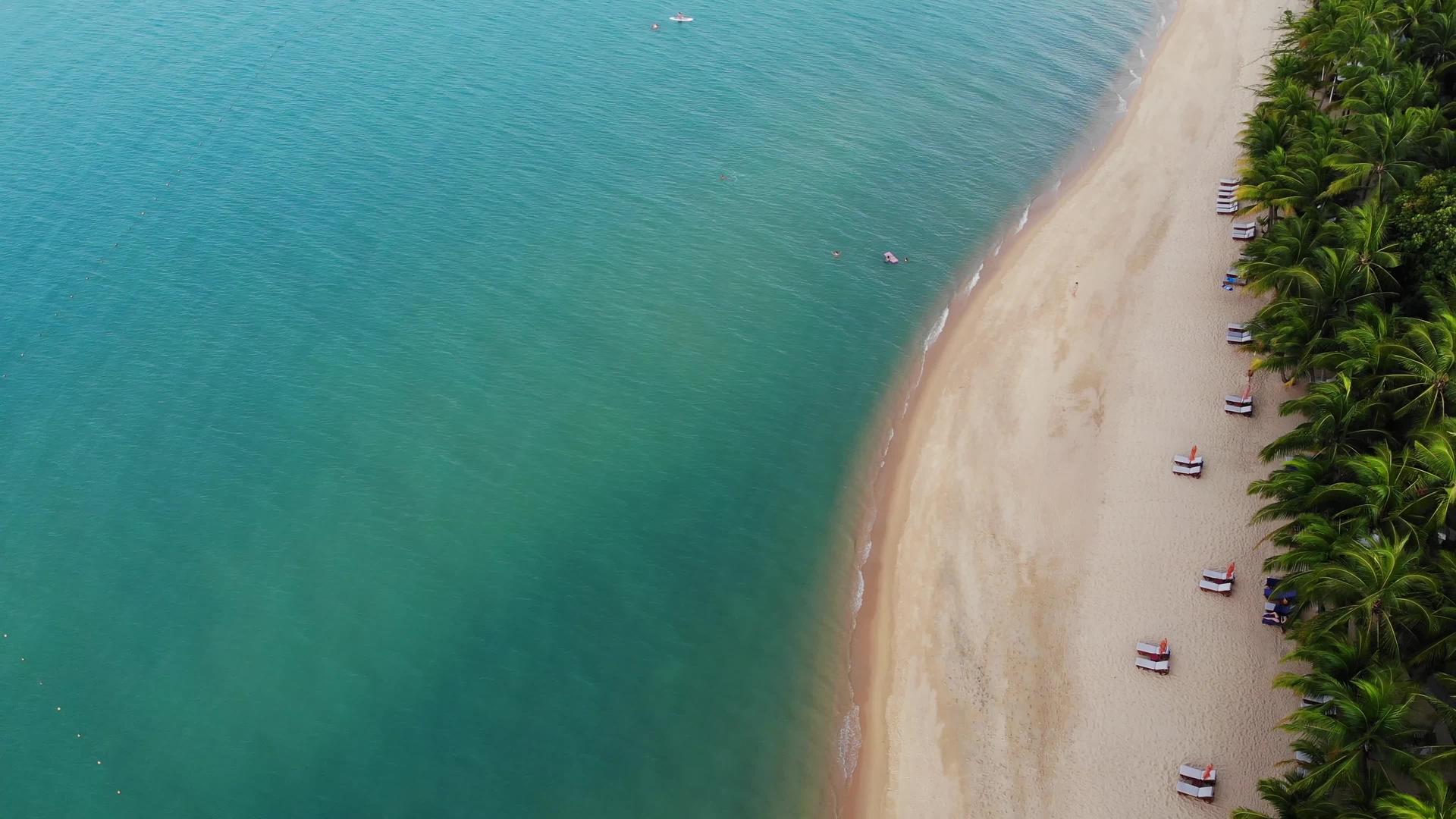 蓝色泻湖和棕榈树海滩上蓝色泻湖和日光浴床的鸟瞰图视频的预览图