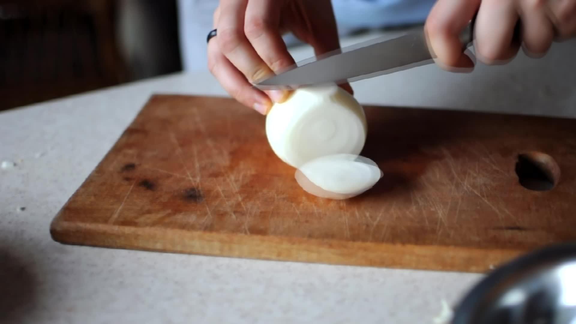女孩把洋葱切成两半用一把锋利的刀把它切成小块视频的预览图