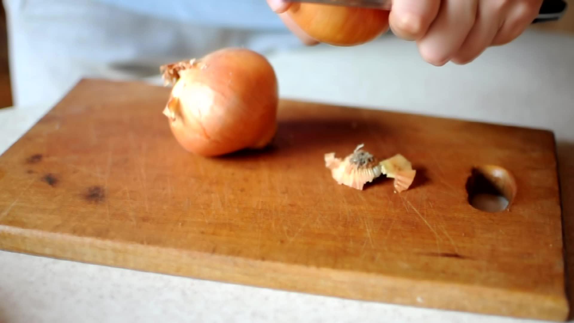一个女人在厨房里剥了多汁的洋葱她用一把大刀割断了洋葱视频的预览图