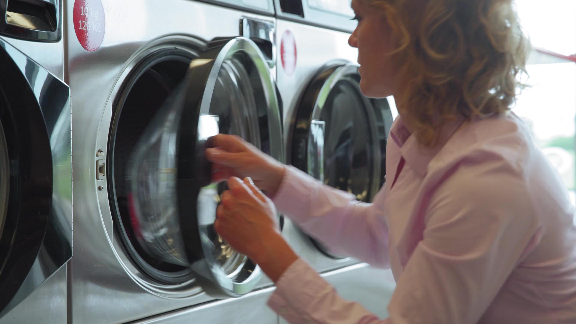 一个年轻女子把脏衣服放进洗衣房的洗衣机里做家务视频的预览图