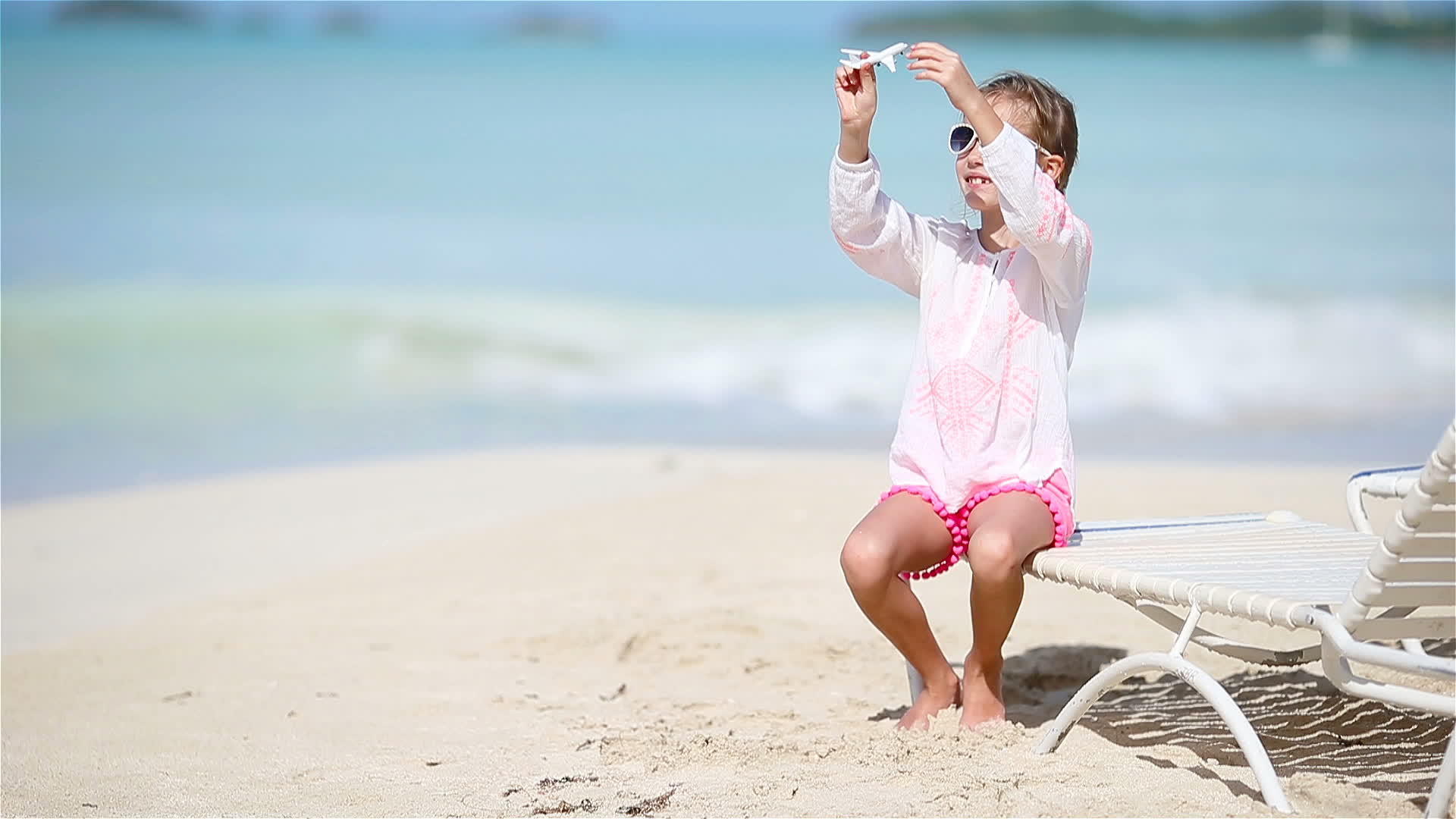 快乐的小女孩手里拿着玩具飞机孩子们在白色的海滩上视频的预览图