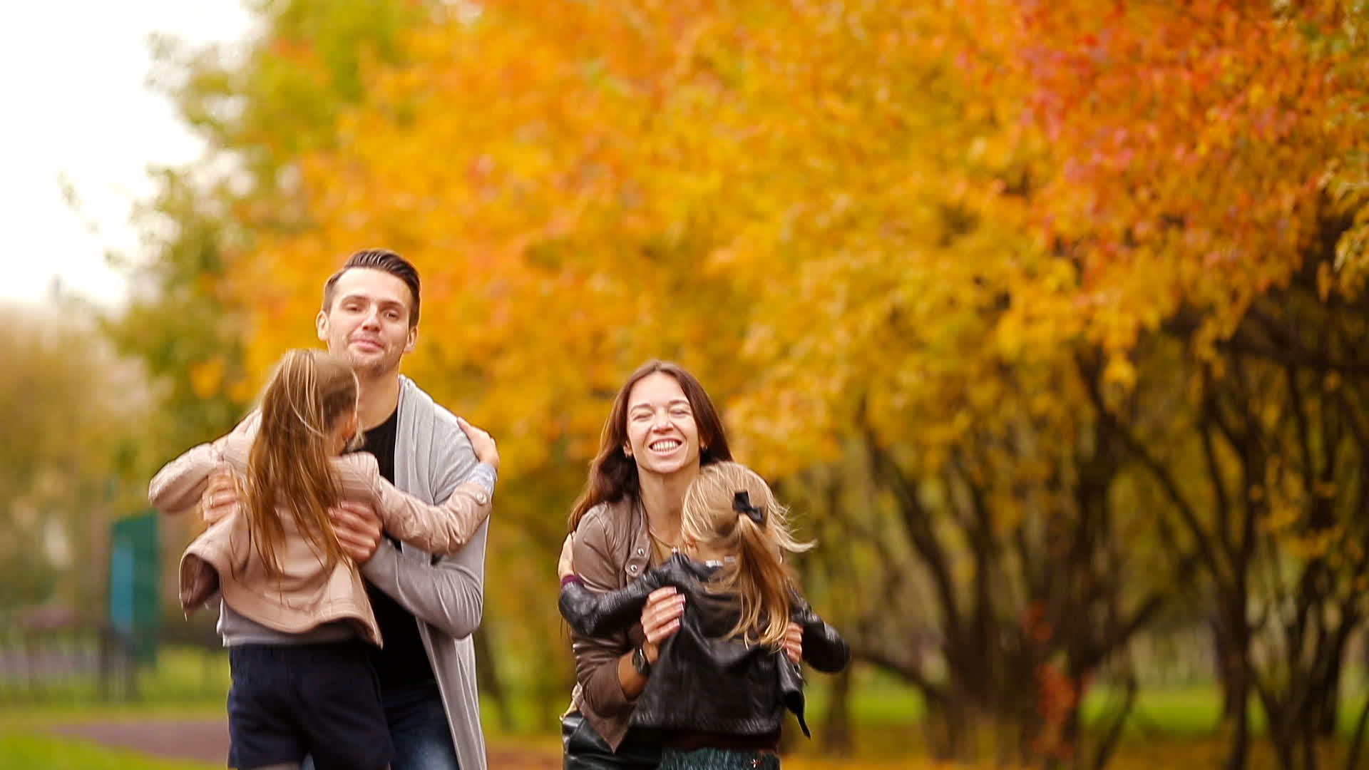 秋天有孩子的年轻家庭在公园里享受温暖的一天视频的预览图
