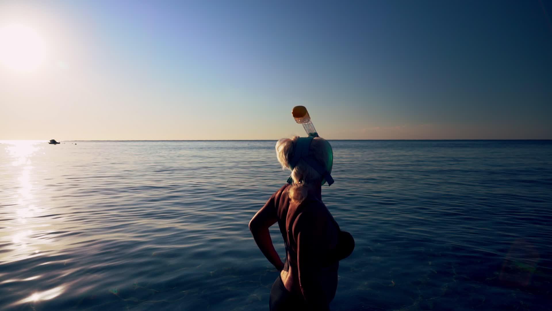 穿着潜水服的女人进入平静的海面视频的预览图