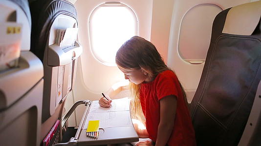 这个可爱的小女孩在飞机上旅行孩子们用彩色铅笔在飞机窗边画画视频的预览图