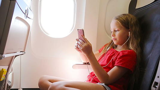 可爱的小女孩坐在窗前坐在飞机窗附近视频的预览图