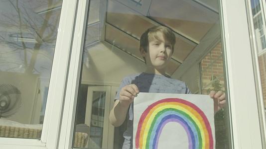 男孩把彩虹的图像贴在窗户上视频的预览图