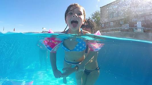 快乐有趣的女孩和她的母亲在热水池里玩耍女孩微笑着从嘴里伸出舌头视频的预览图