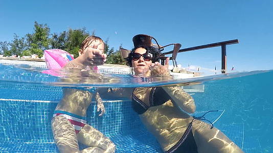 快乐有趣的女孩和她的母亲在热水池里玩耍女孩微笑着从嘴里伸出舌头视频的预览图