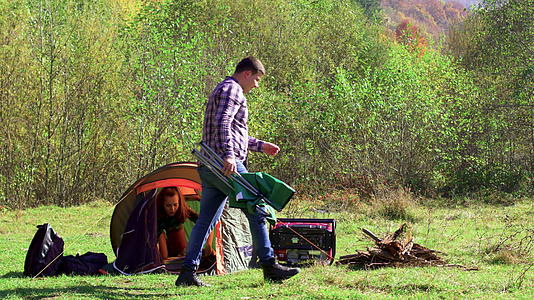 男朋友坐在露营的座位上女朋友正在准备帐篷视频的预览图