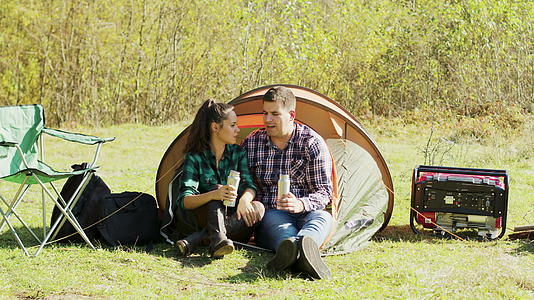 男朋友坐在露营帐篷前亲吻女友的脸颊视频的预览图