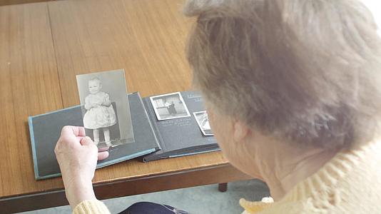 高级女性通过旧照片专辑浏览视频的预览图