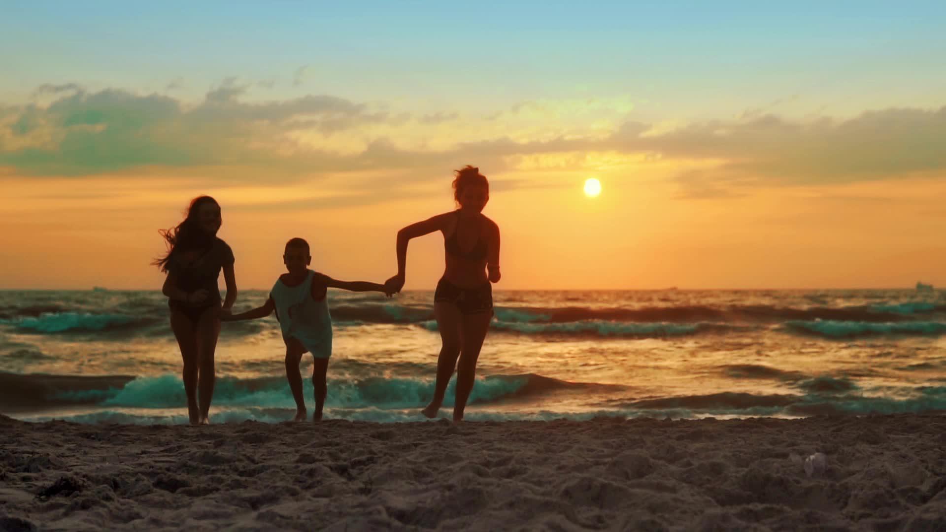 热带海滩日落时三个女孩用光了海水在热带海滩上视频的预览图