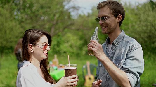 快乐的男孩在公园野餐时和女朋友聊天喝酒视频的预览图