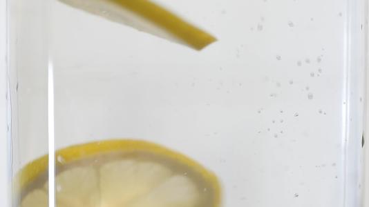 慢动作柠檬溅入有气泡的水中冷鸡尾酒加柠檬健康生活视频的预览图