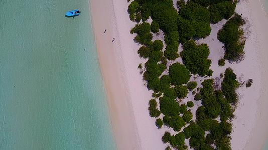 在蓝绿色的大海和棕榈树附近的白色沙滩上航行时阳光明媚的天堂视频的预览图