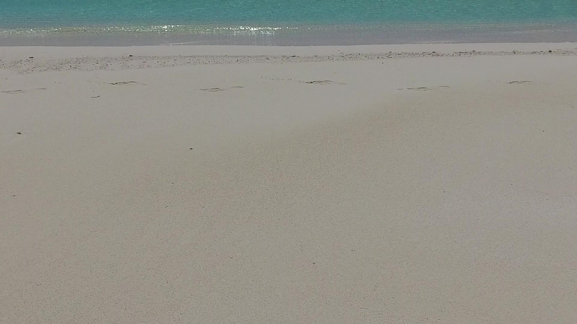 在海浪附近的白沙背景下蓝色环礁湖将探索宁静的海岸海滩视频的预览图