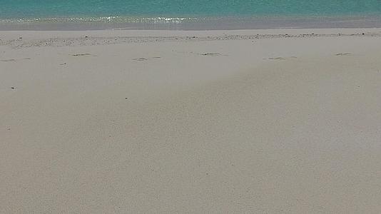 在海浪附近的白沙背景下蓝色环礁湖将探索宁静的海岸海滩视频的预览图