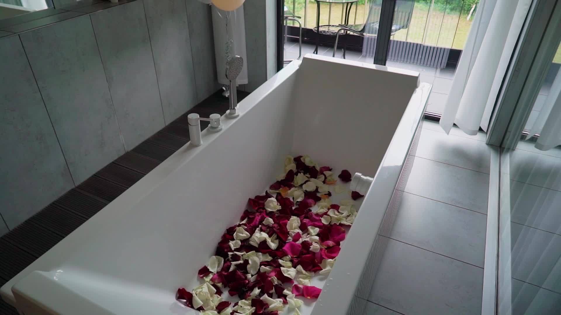 带玫瑰花瓣的浴缸浪漫约会或蜜月约会视频的预览图