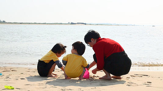 妈妈带孩子在海边玩沙子视频的预览图