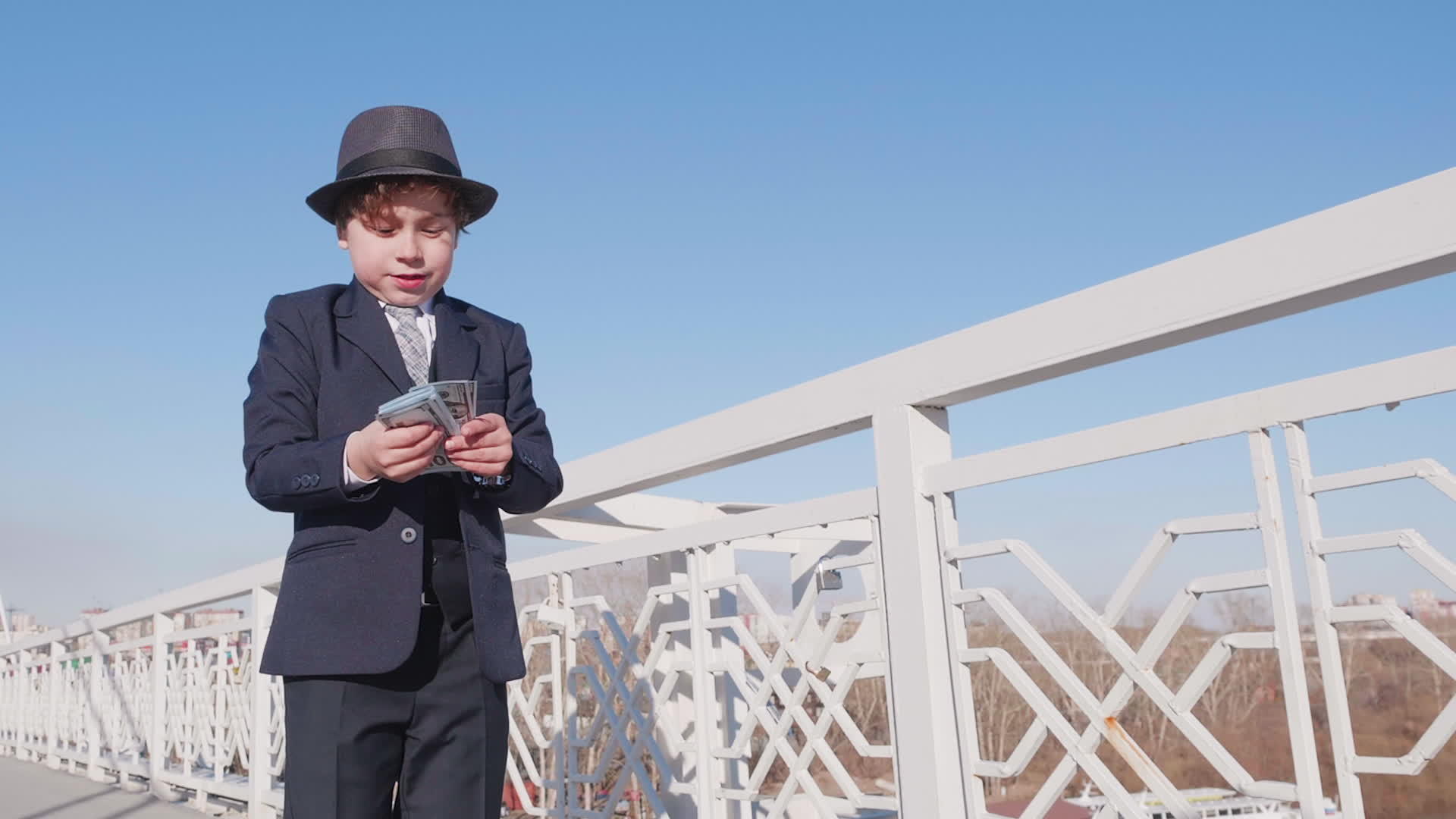 这个男孩看起来像一个商人从桥上的空气中浪费和扔钱视频的预览图