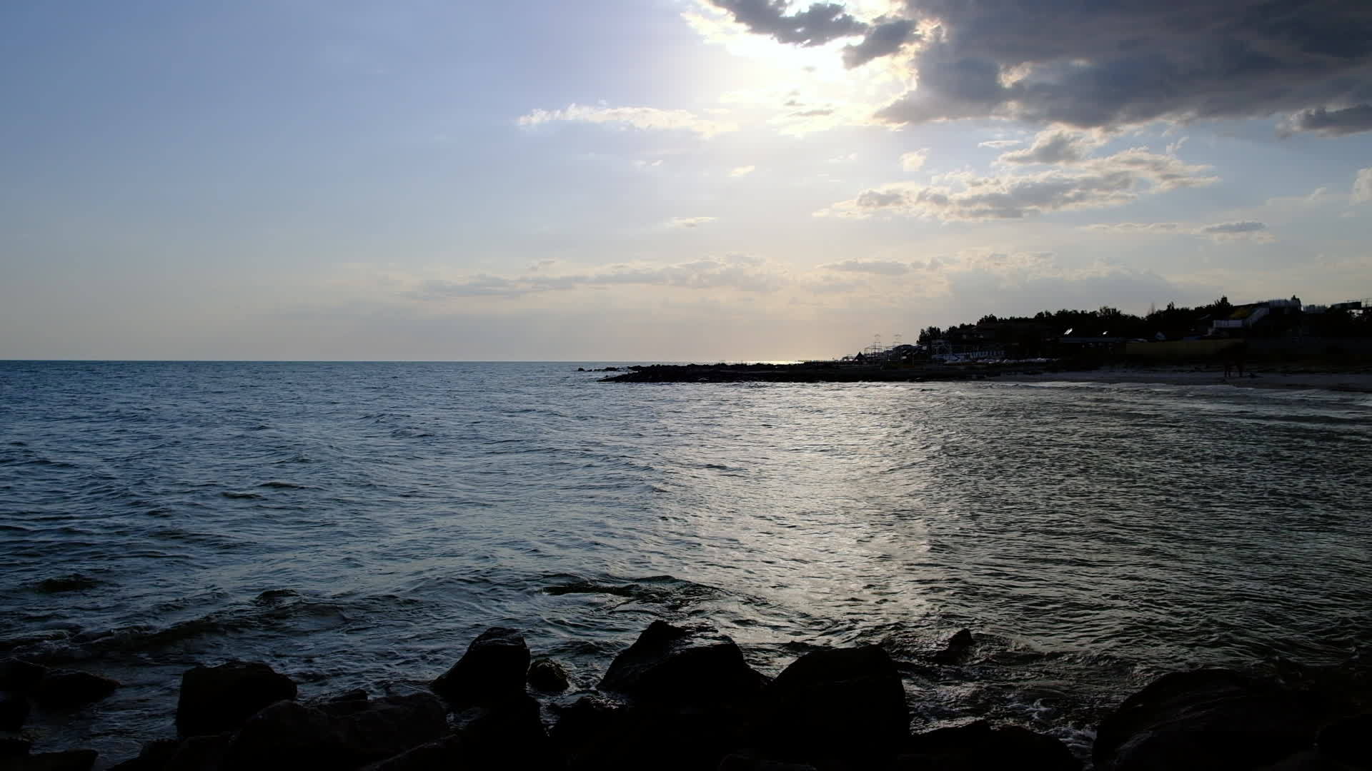 黑色海岸上有大块石头海浪在阳光明媚的夏天席卷视频的预览图