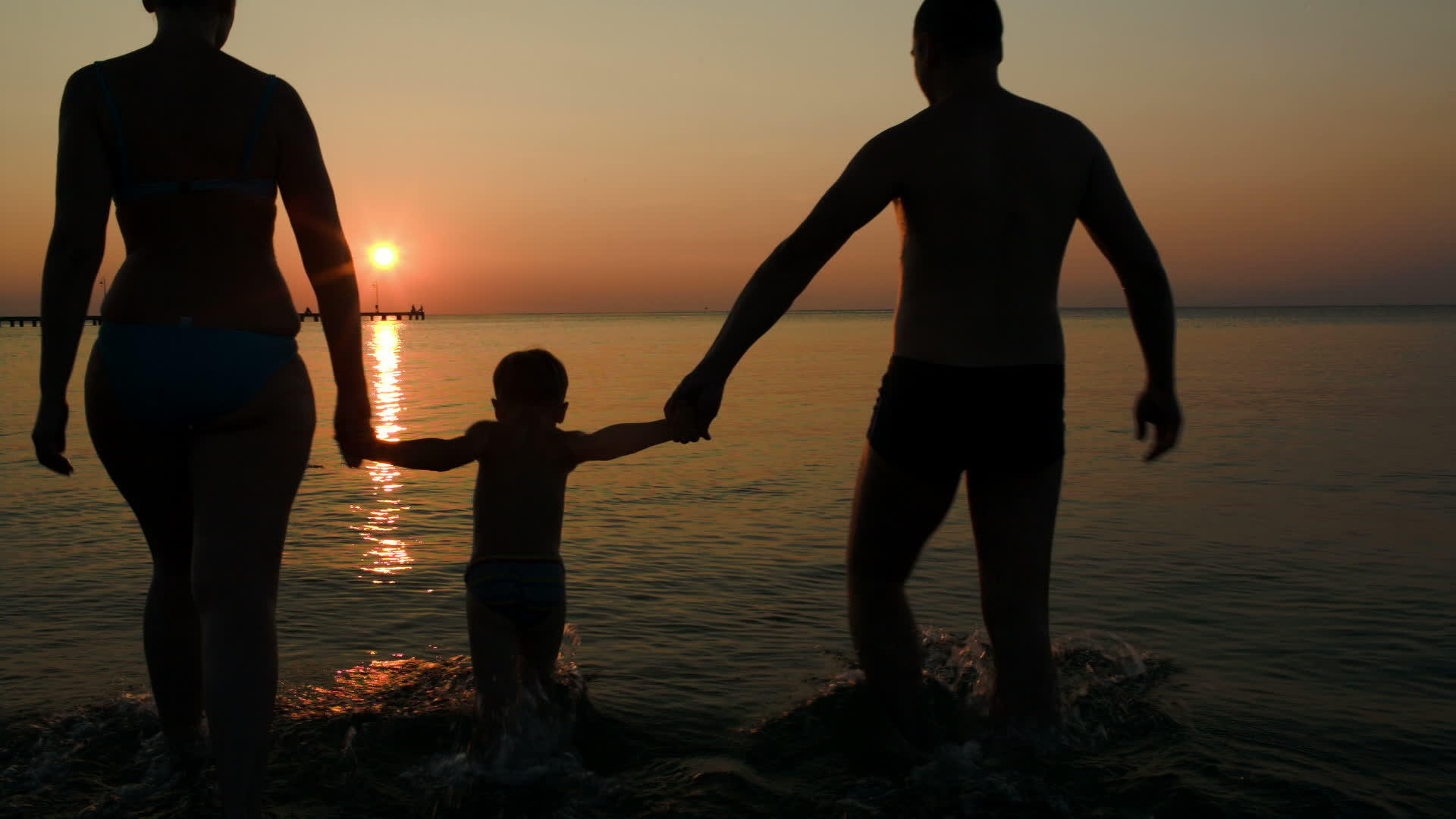 父母和儿子在日落时在海上打球视频的预览图