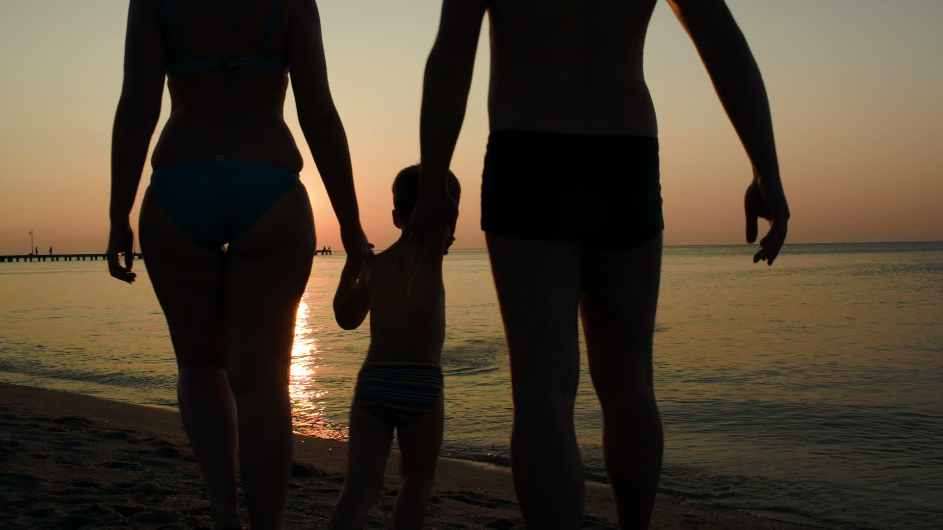父母和孩子在日落时沐浴在海里视频的预览图