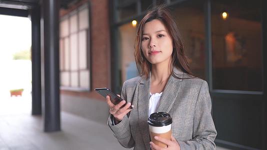 咖啡馆前的职场女生在玩手机喝咖啡视频的预览图