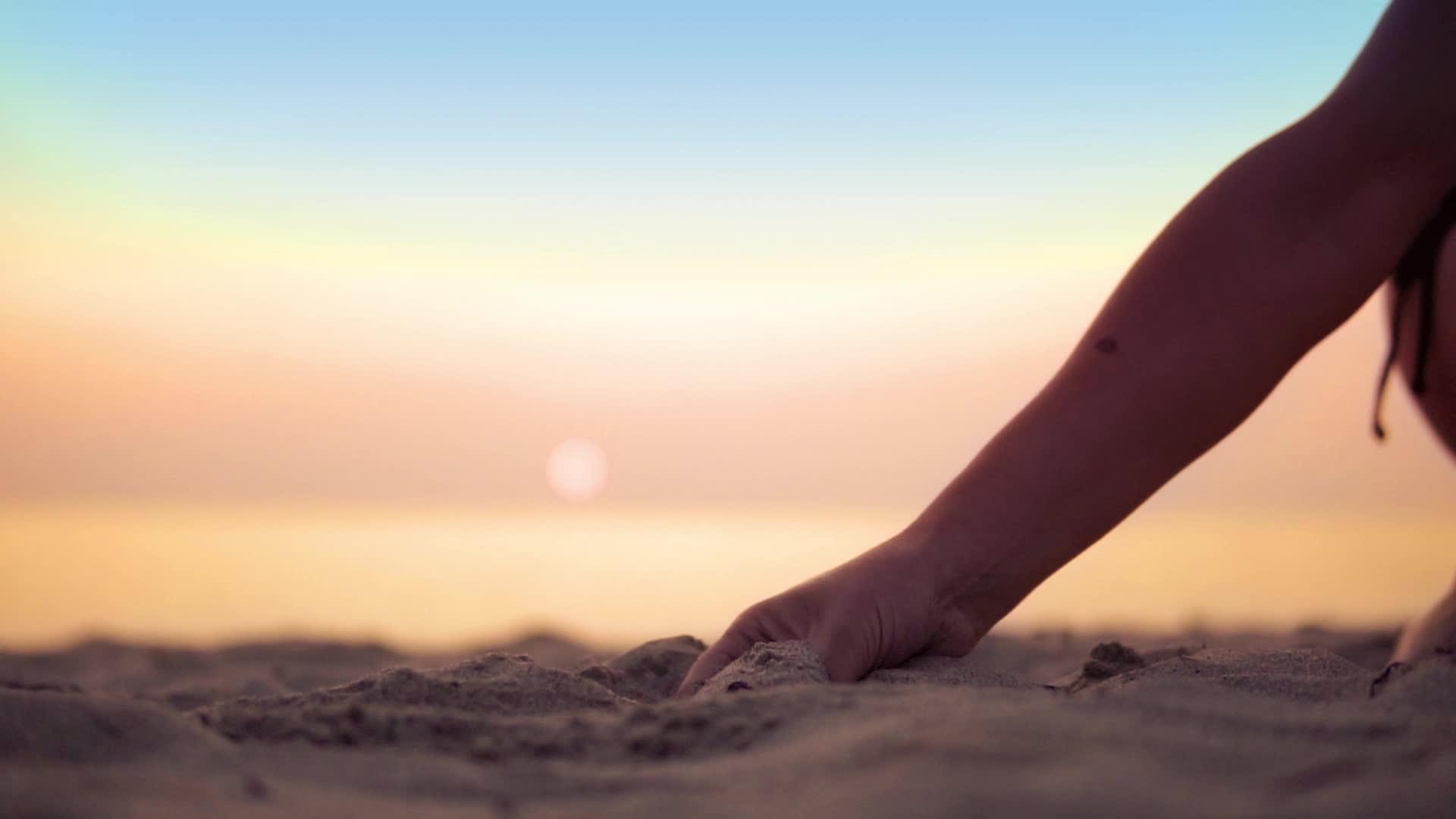日落时沙子落在海滩上的女人慢慢移动视频的预览图