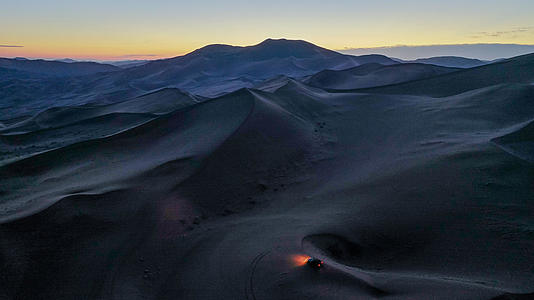 日出前在沙漠中行驶的汽车4k航拍视频视频的预览图