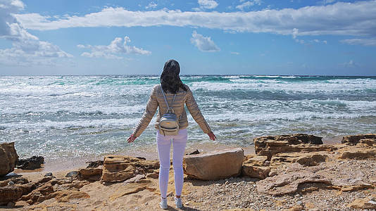 一位年轻女子站在风暴海岸的风中看着地平线视频的预览图