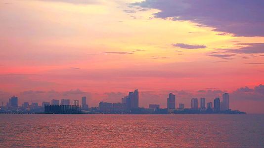 日落的橙色云彩以及以海洋和城市为背景的废弃展馆视频的预览图