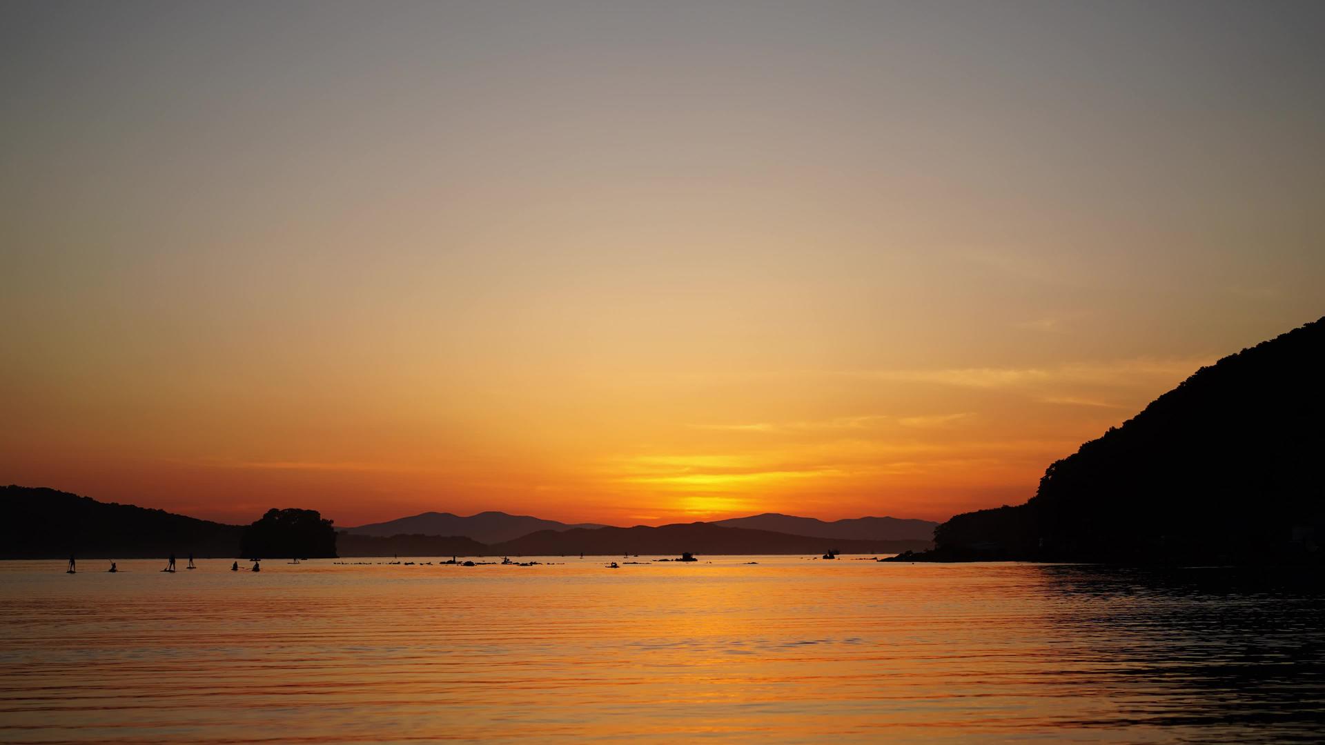 日落时海景和冲浪者在黄昏中漫步视频的预览图