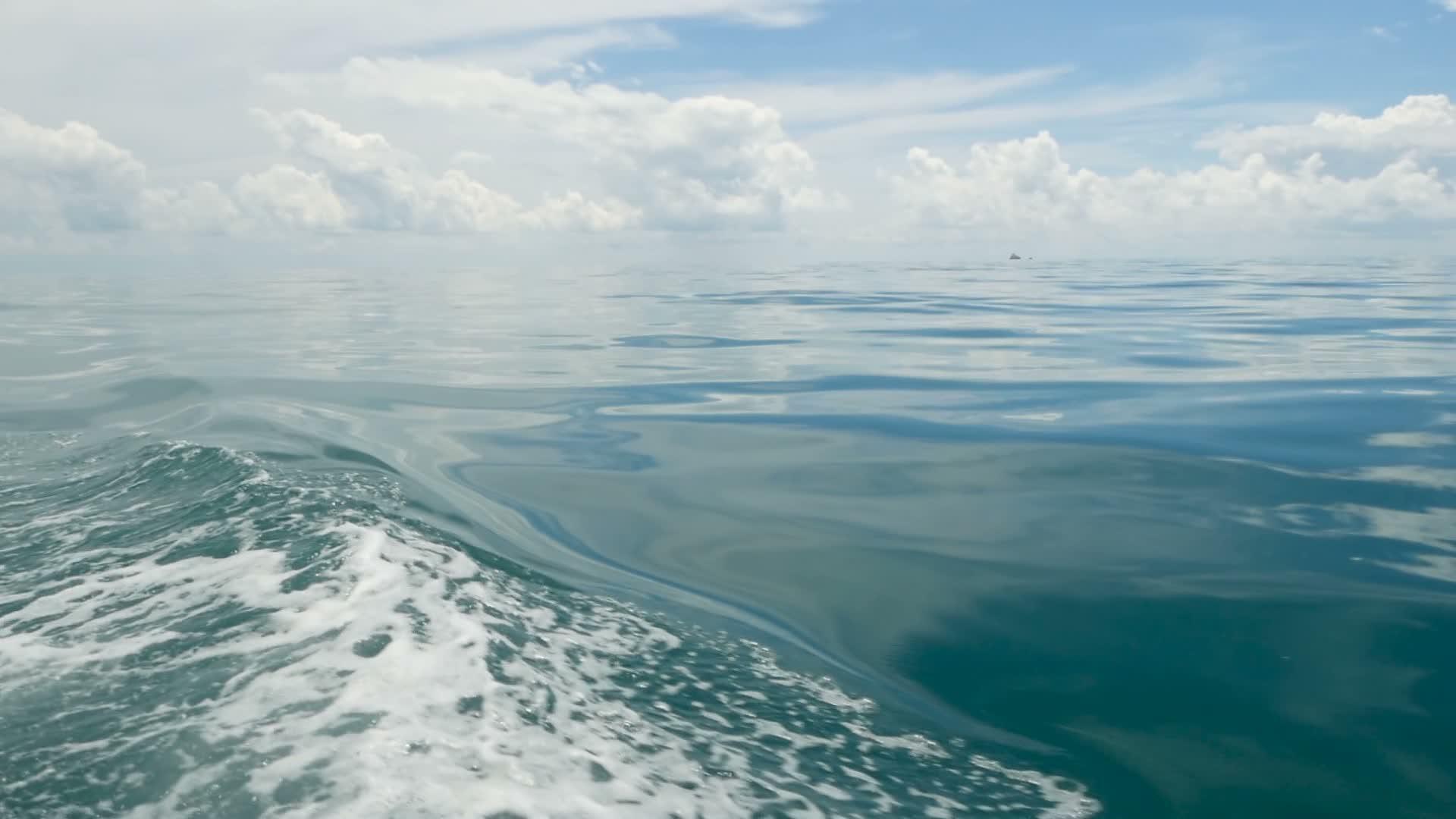 在阴天的小船和平静的海洋之后的小泡沫蓝色波浪田园诗视频的预览图